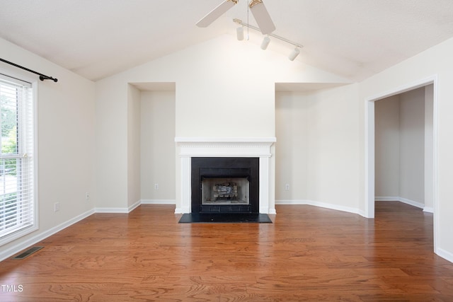 3213 Planet Dr, Raleigh, NC 27604 - unfurnished living room with vaulted ceiling, wood finished floors, a ceiling fan, track lighting, and a fireplace with flush hearth