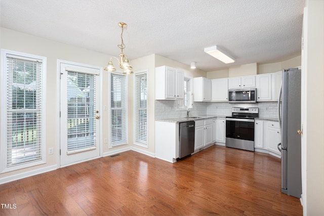 3213 Planet Dr, Raleigh, NC 27604 - kitchen with stainless steel appliances, dark wood-style floors, tasteful backsplash, a chandelier, and white cabinetry