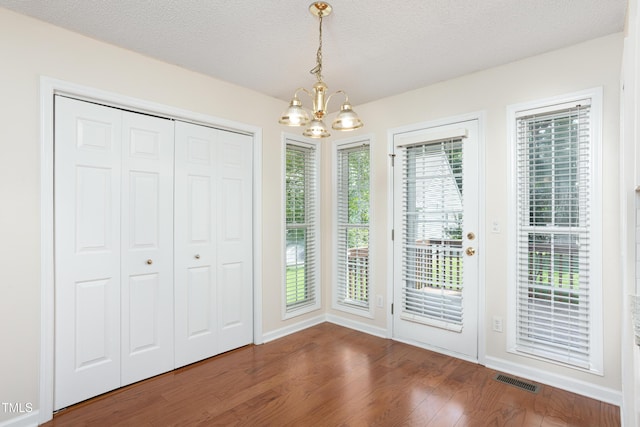 3213 Planet Dr, Raleigh, NC 27604 - unfurnished dining area with a chandelier, wood finished floors, and a textured ceiling
