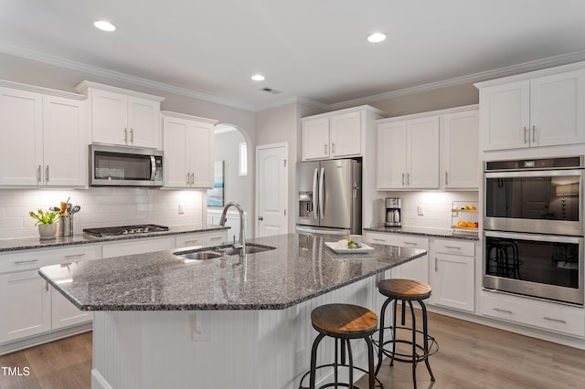 630 Heartland Flyer Dr, Knightdale, NC 27545 - kitchen featuring stainless steel appliances, white cabinetry, backsplash, arched walkways, and ornamental molding