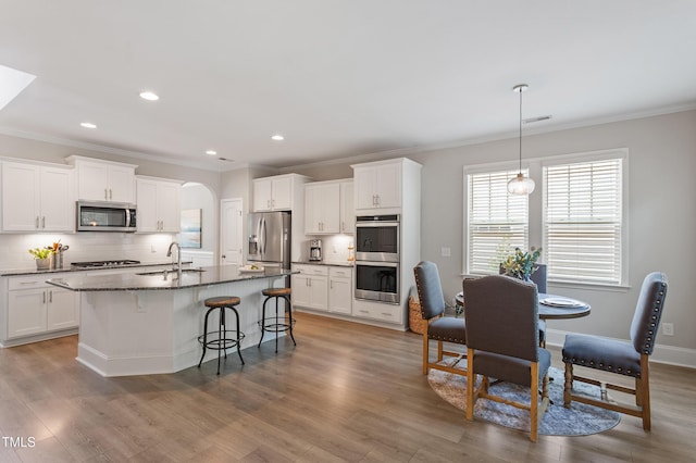 630 Heartland Flyer Dr, Knightdale, NC 27545 - kitchen with stainless steel appliances, ornamental molding, a breakfast bar, decorative backsplash, and arched walkways