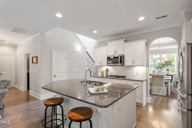 630 Heartland Flyer Dr, Knightdale, NC 27545 - kitchen featuring appliances with stainless steel finishes, a kitchen bar, a center island with sink, light wood-style floors, and backsplash