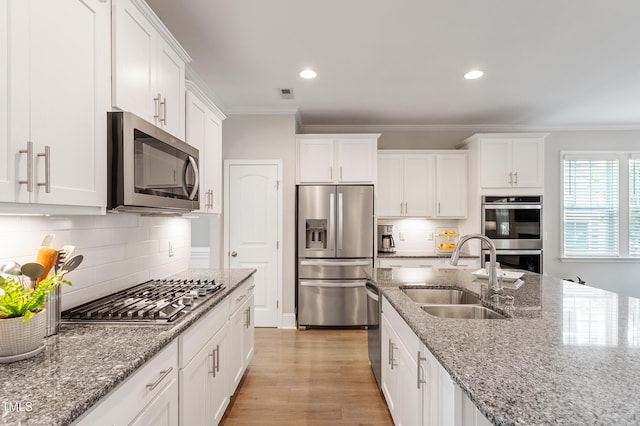 630 Heartland Flyer Dr, Knightdale, NC 27545 - kitchen with appliances with stainless steel finishes, crown molding, white cabinets, backsplash, and light stone countertops