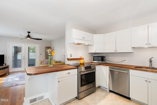 1701 Ruffin St, Durham, NC 27701 - kitchen with stainless steel appliances, wooden counters, under cabinet range hood, and a peninsula