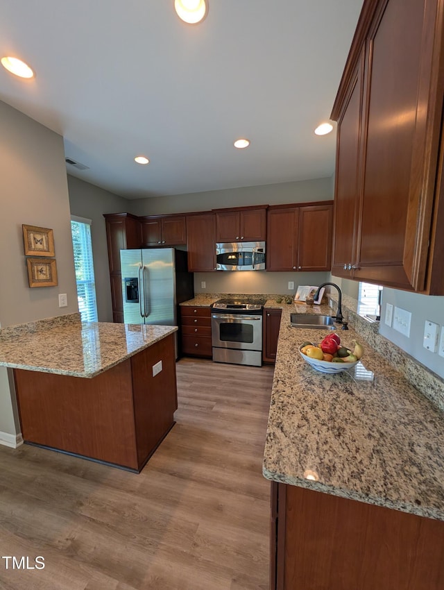 4221 Del Webb Ave, Cary, NC 27519 - kitchen featuring appliances with stainless steel finishes, a peninsula, healthy amount of natural light, light stone counters, and recessed lighting