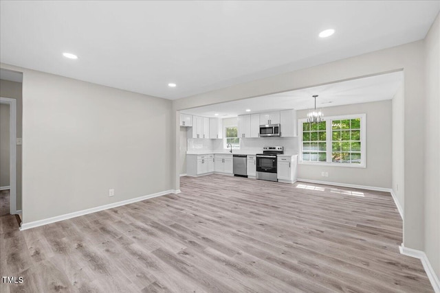 691 Oak Grove Rd, Roxboro, NC 27574 - unfurnished living room with light wood finished floors, a chandelier, and recessed lighting