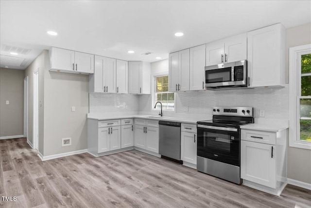 691 Oak Grove Rd, Roxboro, NC 27574 - kitchen with stainless steel appliances, white cabinets, light wood-style flooring, light countertops, and backsplash