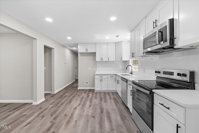 691 Oak Grove Rd, Roxboro, NC 27574 - kitchen with stainless steel appliances, backsplash, light wood-style flooring, white cabinetry, and recessed lighting