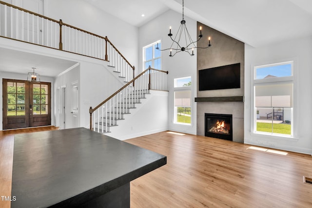 6928 Will Let Ln, Wake Forest, NC 27587 - unfurnished living room with wood finished floors, high vaulted ceiling, a chandelier, stairs, and french doors