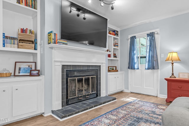 6311 New Market Way, Raleigh, NC 27615 - living room featuring wood finished floors, a tiled fireplace, and built in shelves