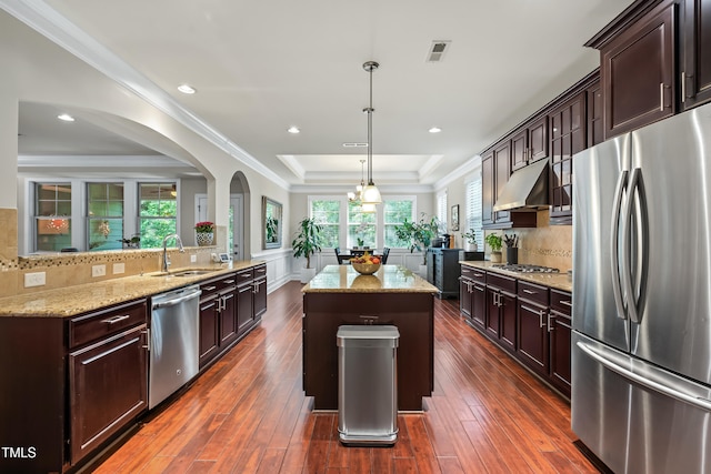 5116 Trembath Ln, Cary, NC 27519 - kitchen featuring stainless steel appliances, a raised ceiling, a kitchen island, light stone counters, and backsplash