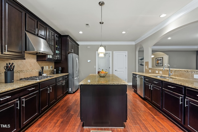 5116 Trembath Ln, Cary, NC 27519 - kitchen featuring under cabinet range hood, arched walkways, a kitchen island, appliances with stainless steel finishes, and light stone counters