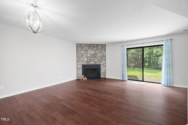 122 Woodbridge Ln, Chapel Hill, NC 27514 - unfurnished living room with a chandelier, a textured ceiling, wood finished floors, and a stone fireplace