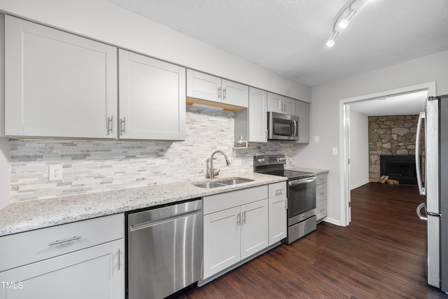 122 Woodbridge Ln, Chapel Hill, NC 27514 - kitchen featuring stainless steel appliances, dark wood-style flooring, a fireplace, light stone countertops, and a textured ceiling