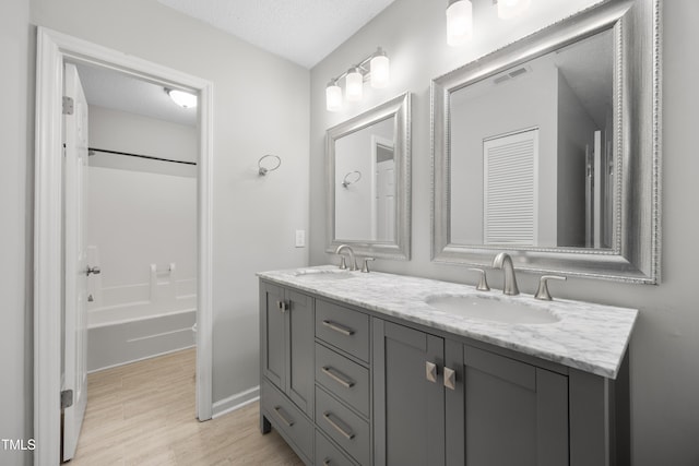 122 Woodbridge Ln, Chapel Hill, NC 27514 - bathroom with double vanity, wood finished floors, shower / bath combination, and a textured ceiling