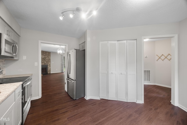 122 Woodbridge Ln, Chapel Hill, NC 27514 - kitchen with stainless steel appliances, dark wood-type flooring, a stone fireplace, light stone countertops, and a textured ceiling