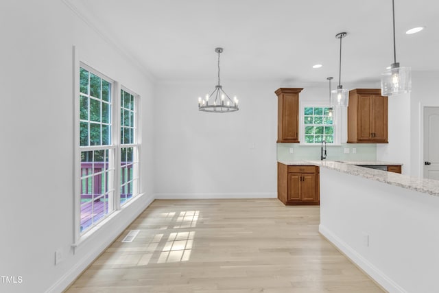 2103 Troys Trl, Franklinton, NC 27525 - kitchen featuring plenty of natural light, crown molding, brown cabinetry, a chandelier, and pendant lighting
