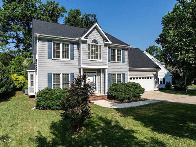 103 Glenstone Ln, Cary, NC 27518 - colonial house featuring an attached garage, concrete driveway, a front yard, and a shingled roof