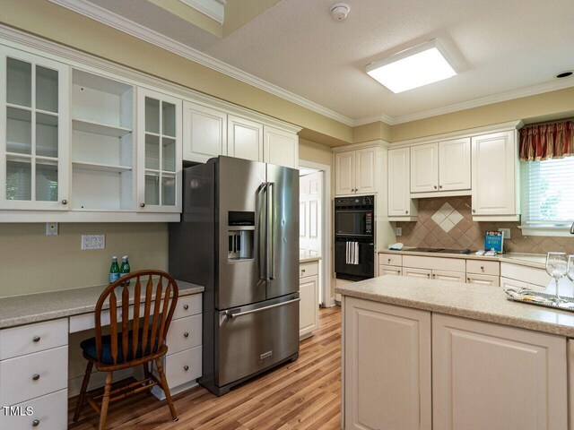 103 Glenstone Ln, Cary, NC 27518 - kitchen featuring black appliances, ornamental molding, built in desk, light wood-style floors, and light countertops