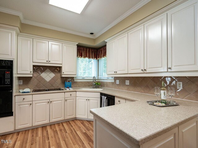 103 Glenstone Ln, Cary, NC 27518 - kitchen featuring black appliances, light wood-type flooring, light countertops, crown molding, and white cabinets