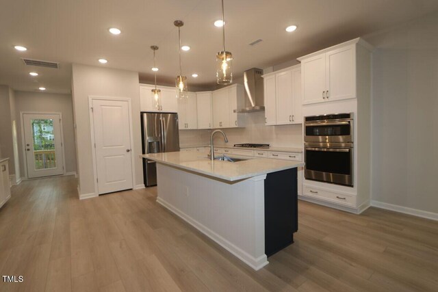 2721 Hunter Woods Dr # 565, Apex, NC 27502 - kitchen featuring wall chimney range hood, stainless steel appliances, light wood-style flooring, light countertops, and white cabinetry
