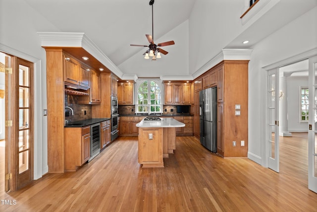3604 Eden Croft Dr, Raleigh, NC 27612 - kitchen with light wood-style flooring, brown cabinets, decorative backsplash, ceiling fan, and freestanding refrigerator