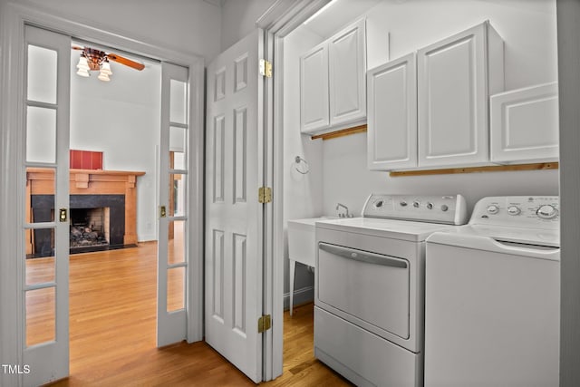 3604 Eden Croft Dr, Raleigh, NC 27612 - laundry room with cabinet space, separate washer and dryer, light wood-type flooring, a tile fireplace, and a ceiling fan