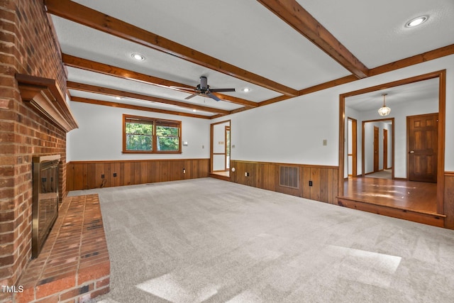 12501 Hardee Rd, Raleigh, NC 27614 - unfurnished living room with a wainscoted wall, beam ceiling, carpet, ceiling fan, and a fireplace