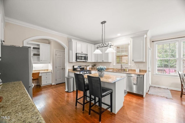 102 Barometer Ln, Cary, NC 27513 - kitchen with stainless steel appliances, ornamental molding, arched walkways, a center island, and white cabinets