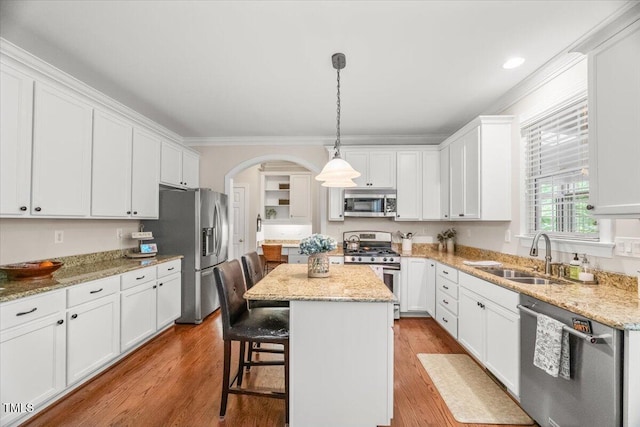 102 Barometer Ln, Cary, NC 27513 - kitchen featuring stainless steel appliances, white cabinetry, arched walkways, ornamental molding, and a center island