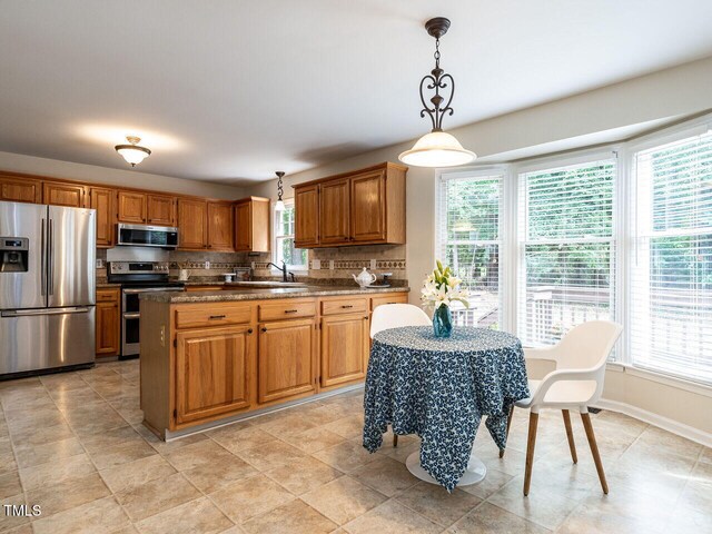 4032 Brook Cross Dr, Apex, NC 27539 - kitchen with appliances with stainless steel finishes, decorative backsplash, hanging light fixtures, dark countertops, and brown cabinetry