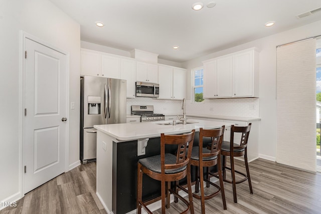 1425 Herb Garden Way, Apex, NC 27502 - kitchen featuring stainless steel appliances, light wood-style floors, decorative backsplash, white cabinets, and light countertops