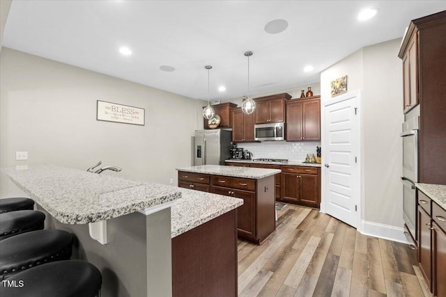 2981 Thurman Dairy, Wake Forest, NC 27587 - kitchen with appliances with stainless steel finishes, a peninsula, light wood finished floors, decorative backsplash, and a center island