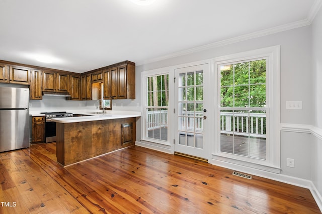 109 Grey Fox Ct, Cary, NC 27511 - kitchen featuring stainless steel appliances, light countertops, under cabinet range hood, a peninsula, and crown molding