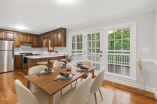 109 Grey Fox Ct, Cary, NC 27511 - kitchen featuring appliances with stainless steel finishes, crown molding, light wood-type flooring, light countertops, and a peninsula