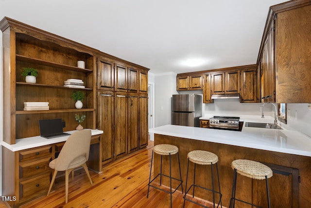 109 Grey Fox Ct, Cary, NC 27511 - kitchen with stainless steel appliances, under cabinet range hood, built in study area, light wood finished floors, and a peninsula