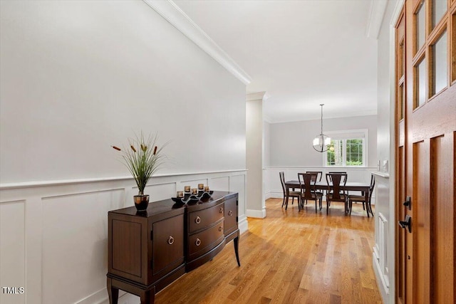 1103 Roosevelt Dr, Chapel Hill, NC 27514 - hall with crown molding, light wood-style floors, wainscoting, a decorative wall, and a chandelier