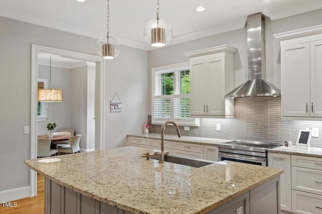 1103 Roosevelt Dr, Chapel Hill, NC 27514 - kitchen featuring wall chimney exhaust hood, decorative backsplash, an island with sink, white cabinetry, and hanging light fixtures