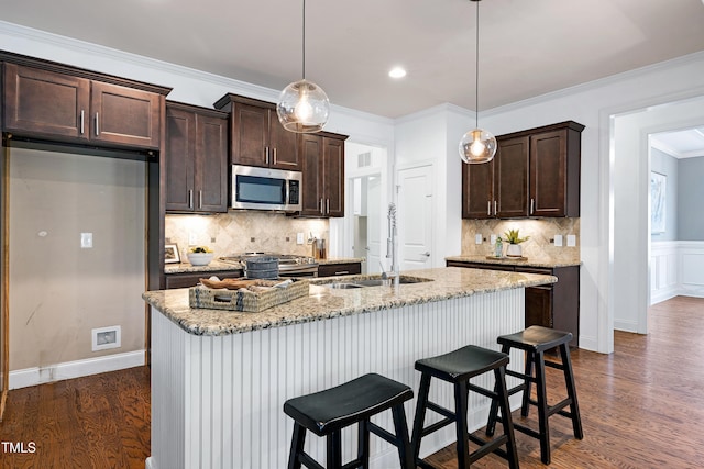 837 Varina Ln, Fuquay Varina, NC 27526 - kitchen featuring appliances with stainless steel finishes, dark brown cabinets, dark wood finished floors, tasteful backsplash, and a breakfast bar area