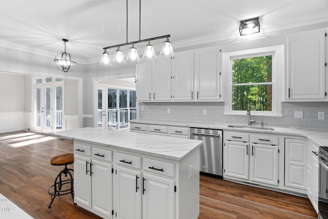 13004 Hanford Ct, Raleigh, NC 27614 - kitchen with dishwasher, a kitchen island, white cabinets, ornamental molding, and a wainscoted wall