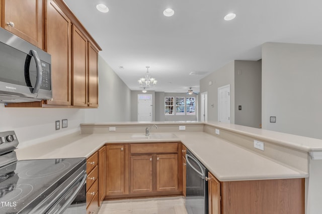 3634 Olympia Dr, Raleigh, NC 27603 - kitchen with appliances with stainless steel finishes, a chandelier, brown cabinets, light countertops, and recessed lighting