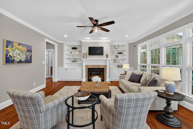 3748 Knollcreek Dr, Apex, NC 27539 - living area with wood finished floors, ceiling fan, a tiled fireplace, crown molding, and built in features