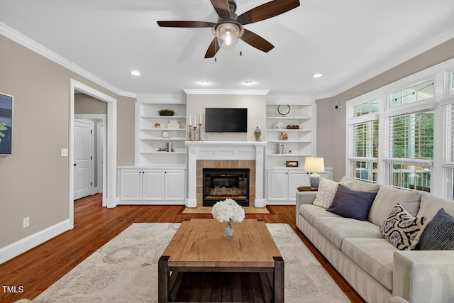 3748 Knollcreek Dr, Apex, NC 27539 - living room featuring a tiled fireplace, wood finished floors, crown molding, a ceiling fan, and built in shelves