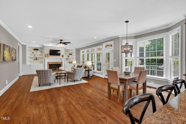 3748 Knollcreek Dr, Apex, NC 27539 - dining space with crown molding, a ceiling fan, healthy amount of natural light, a fireplace, and wood finished floors