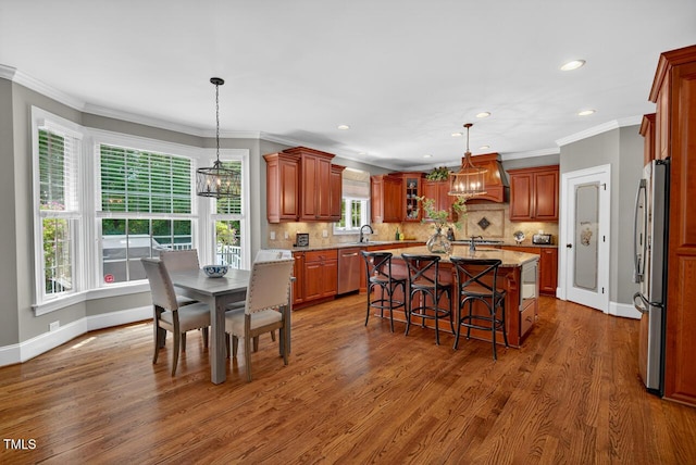 3748 Knollcreek Dr, Apex, NC 27539 - kitchen featuring a chandelier, stainless steel appliances, an island with sink, wood finished floors, and ornamental molding
