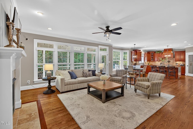 3748 Knollcreek Dr, Apex, NC 27539 - living room with crown molding, recessed lighting, a ceiling fan, a fireplace with flush hearth, and light wood-type flooring