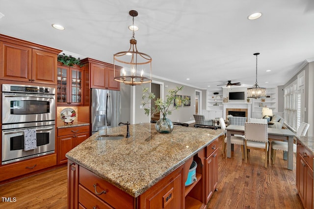 3748 Knollcreek Dr, Apex, NC 27539 - kitchen with appliances with stainless steel finishes, a fireplace, crown molding, a chandelier, and a center island with sink