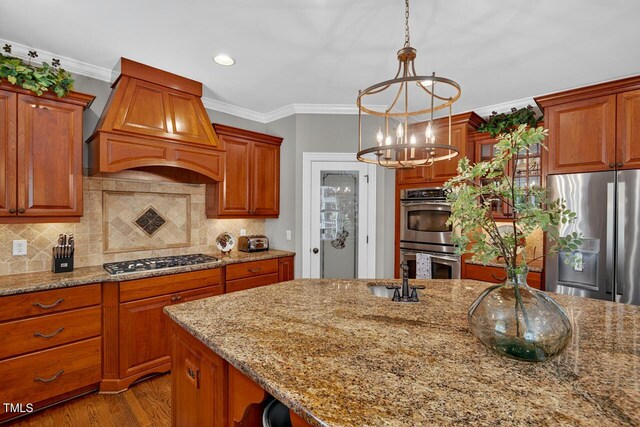 3748 Knollcreek Dr, Apex, NC 27539 - kitchen with stainless steel appliances, premium range hood, a chandelier, ornamental molding, and light stone counters