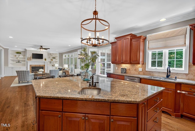 3748 Knollcreek Dr, Apex, NC 27539 - kitchen with a ceiling fan, a tiled fireplace, an island with sink, light stone counters, and a chandelier