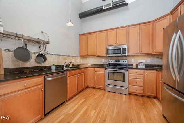 1535 Caraleigh Mills Ct Unit 142, Raleigh, NC 27603 - kitchen with appliances with stainless steel finishes, tasteful backsplash, light wood-style floors, a high ceiling, and brown cabinets